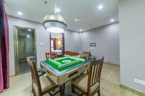 A hotel room with a dining table, four chairs, a ceiling light fixture, and a mirror on the wall.
