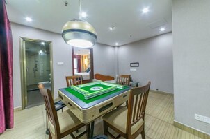 Una habitación de hotel con una mesa de comedor, cuatro sillas, una lámpara en el techo y un espejo en la pared.