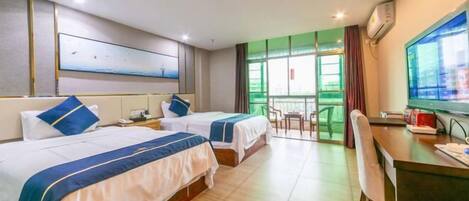 Habitación de hotel con dos camas, un escritorio, una silla, un televisor y un balcón con vistas.