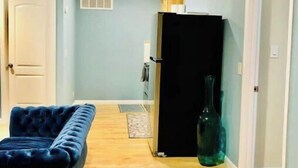 A room with a blue sofa, a black refrigerator, and a wooden floor. - Great View Guest Unit/Near Eden Hospital/Kaiser SL (San Leandro)