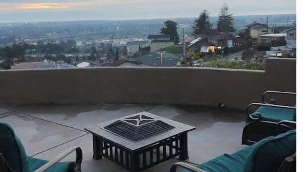 An outdoor patio with wicker furniture and a table, overlooking a residential area. - Great View Guest Unit/Near Eden Hospital/Kaiser SL (San Leandro)