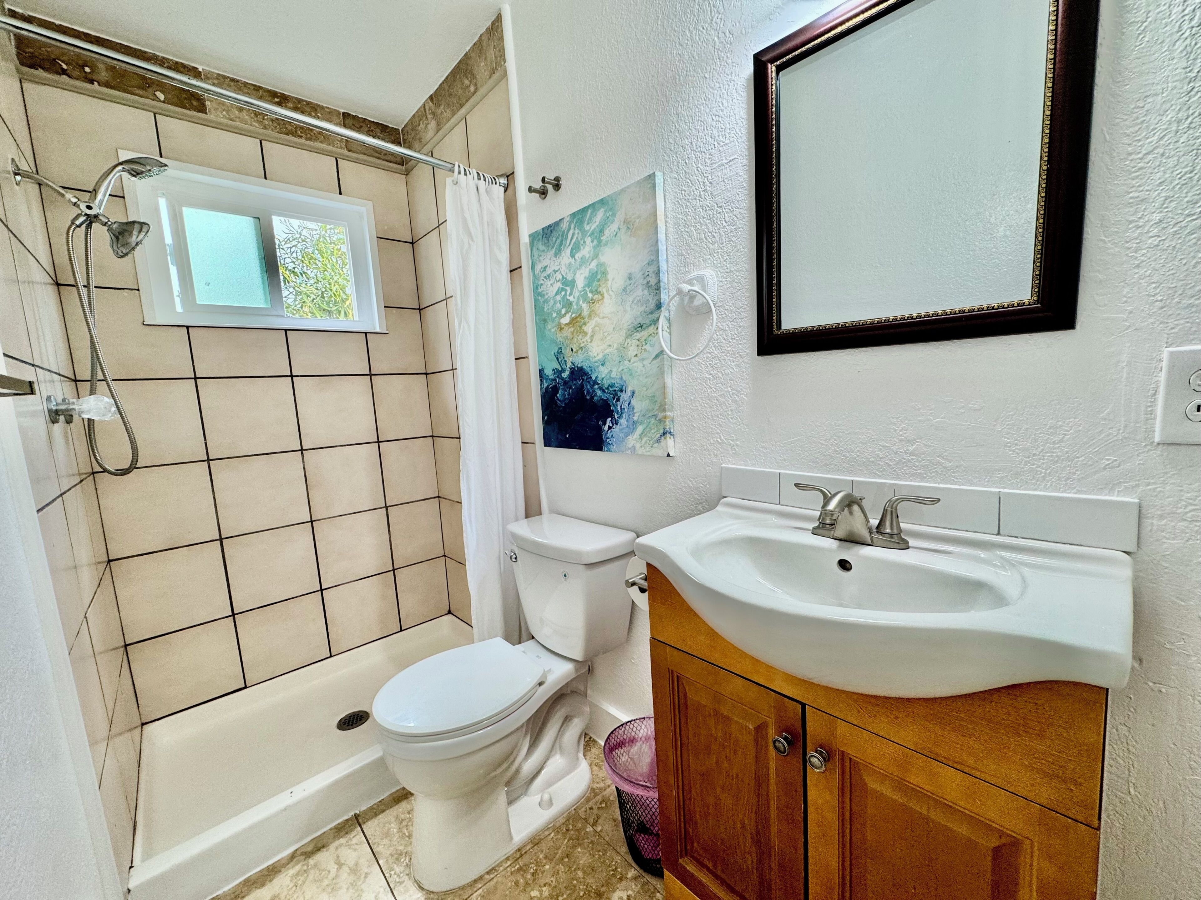Ein Badezimmer mit Badewanne, Toilette, Waschbecken und einem Fenster.