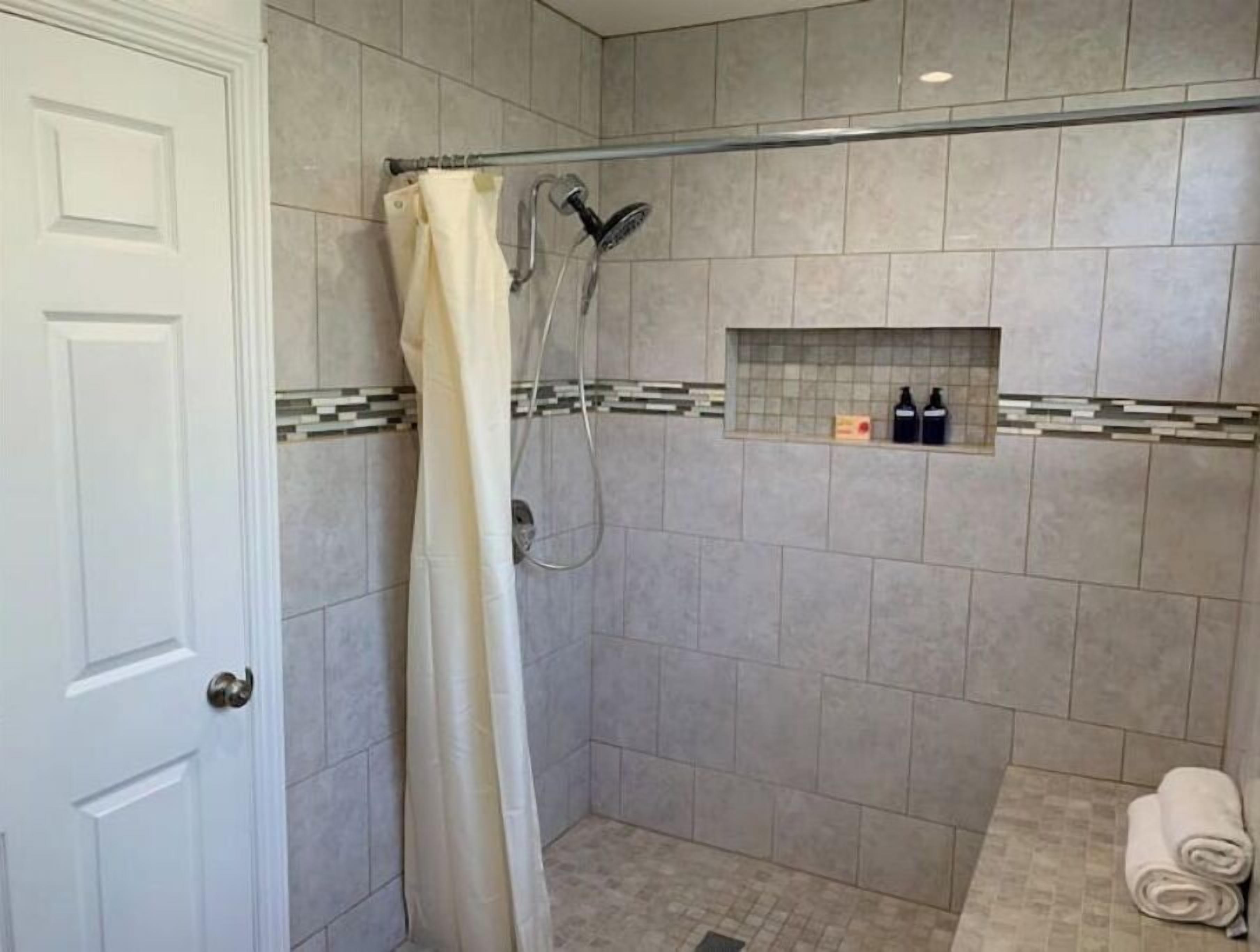 Une salle de bain avec une douche, un porte-serviettes et une petite étagère contenant des articles de toilette.
