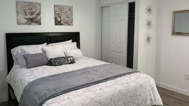 Een slaapkamer met een bed, witte wanden en twee schilderijen.