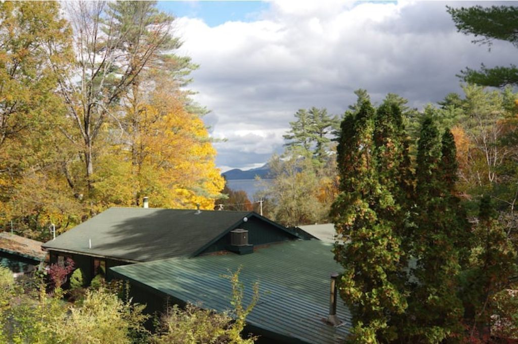 A house with a green roof surrounded by trees with autumn foliage.