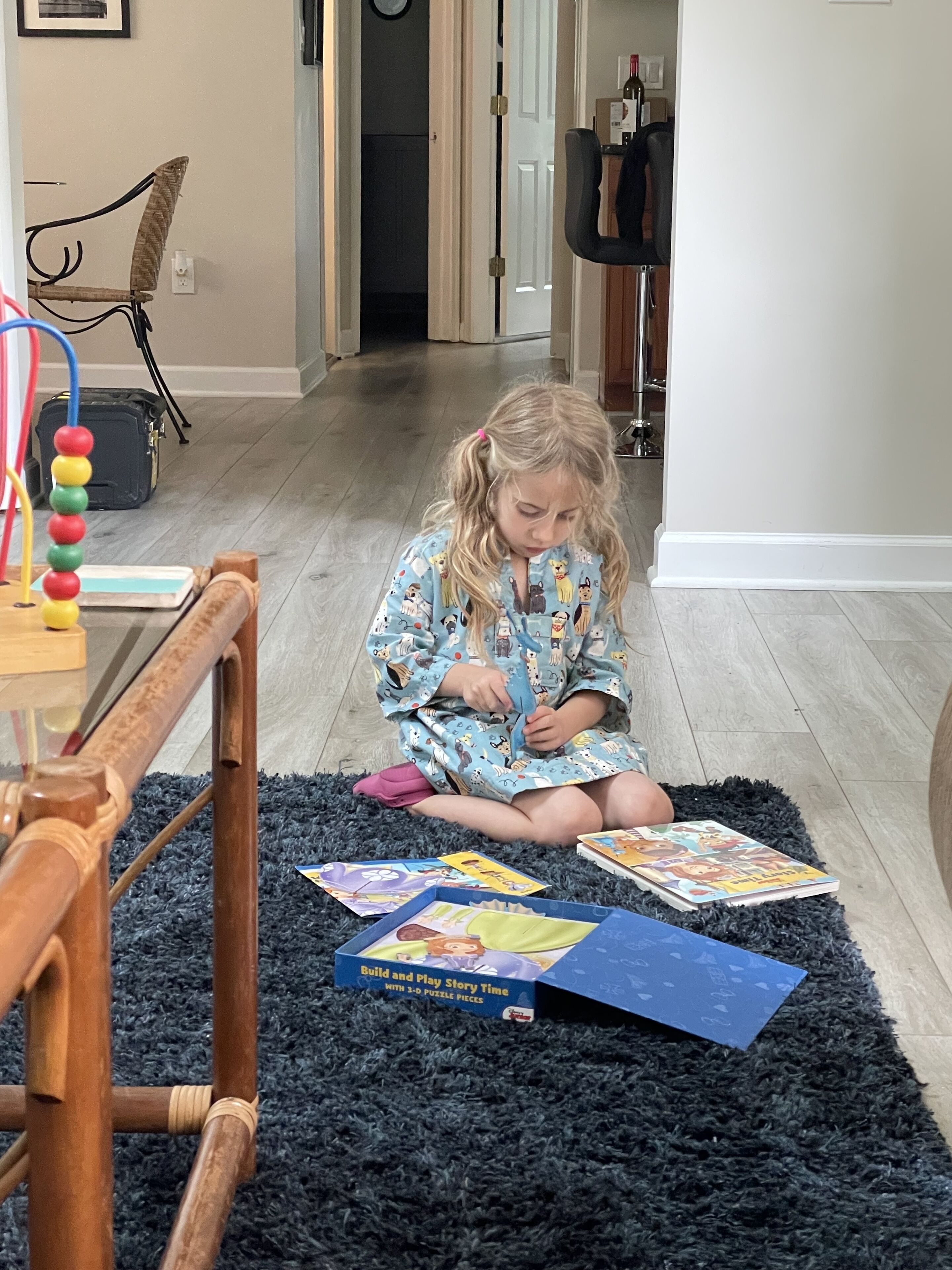 A child sitting on a dark rug, playing with puzzle pieces.
