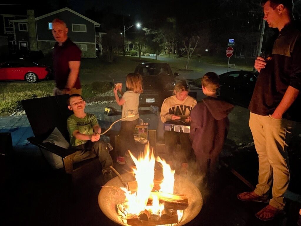 Eine Gruppe Menschen sitzt nachts an einem Lagerfeuer.