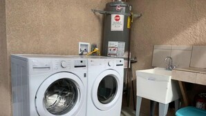 A laundry area with two front-loading washing machines, a water heater, and a sink. - Private Studio/Downtown/Free Washer/Dryer/Fast Wi-Fi (Castro Valley)