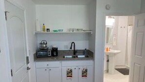 A compact kitchen with white cabinets, a countertop with a kettle, toaster, and coffee maker, and a sink. - Private Studio/Downtown/Free Washer/Dryer/Fast Wi-Fi (Castro Valley)