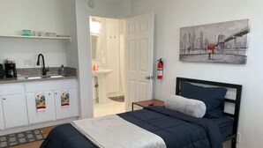 A bedroom with a bed, a nightstand, a painting, and a view of the bathroom. - Private Studio/Downtown/Free Washer/Dryer/Fast Wi-Fi (Castro Valley)