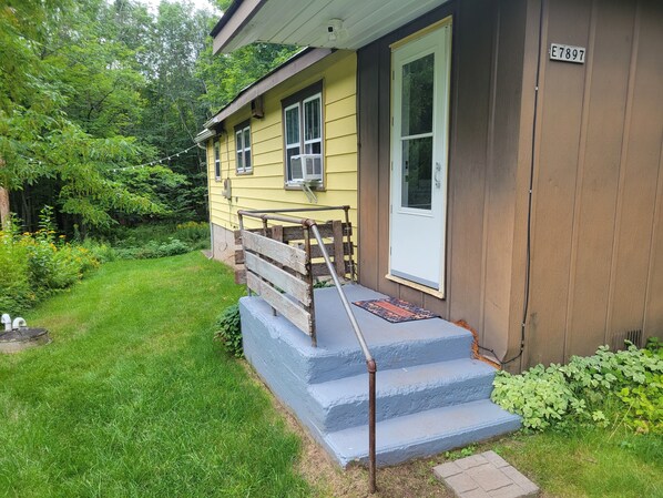A yellow house with a brown exterior, a front door, and a number plate E7897. - Cabin on 25 Acres of Forest (Bessemer)