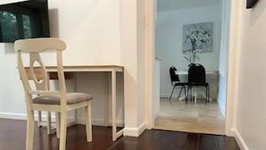 Ein Essbereich mit Holztisch und -stühlen, einem dunklen Holzboden und einem Gemälde an der Wand.