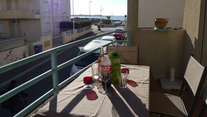 Un balcon avec une table dressée pour deux personnes, agrémentée d’une bouteille de vin, de verres et d’une bouteille d’eau.