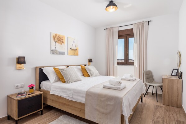 A neatly arranged bedroom with a bed, bedside tables, a chair, and a small desk. - Cozy villa with amazing view from terrace, pool, close to the beach (Kostrena)