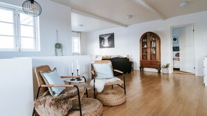 Una habitación amplia con piso de madera, un gran armario abovedado y una zona de estar acogedora con sillas de mimbre y un plaid de piel.