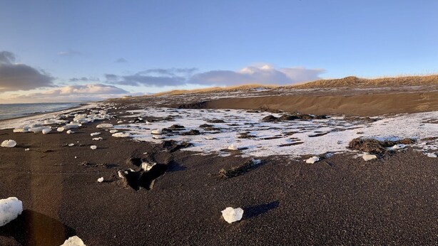 Una playa con formaciones de hielo y un atardecer.