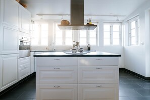 A spacious kitchen with white cabinetry, a central island, and a large window providing natural light.