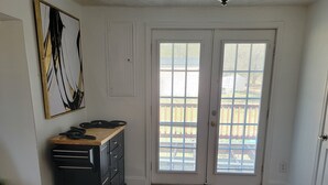 Una stanza spaziosa con parquet, una cucina a isola nera e una porta scorrevole in vetro che dà su un balcone.