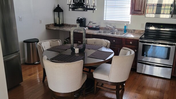 Una cucina moderna con zona pranzo, elettrodomestici in acciaio inossidabile e un lampadario.