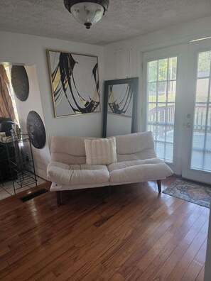 A living room with a beige sofa, wooden flooring, and artwork on the walls.