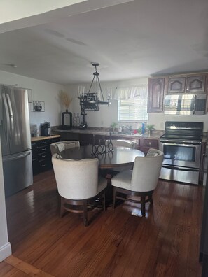 A modern kitchen with a central island, stainless steel appliances, and a dining area with chairs.