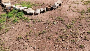 Un giardino con un vialetto a forma di cuore in pietra e una struttura circolare in pietra.