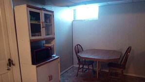A room with a dining table and chairs, a cabinet with glass doors, and a window providing natural light. - Walk in basement apartment - near downtown Norfolk (Norfolk)