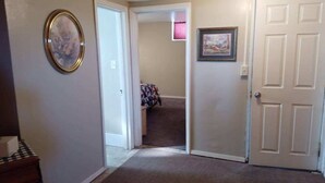 A hallway with a carpeted floor, a door on the right, and a framed picture on the left. - Walk in basement apartment - near downtown Norfolk (Norfolk)