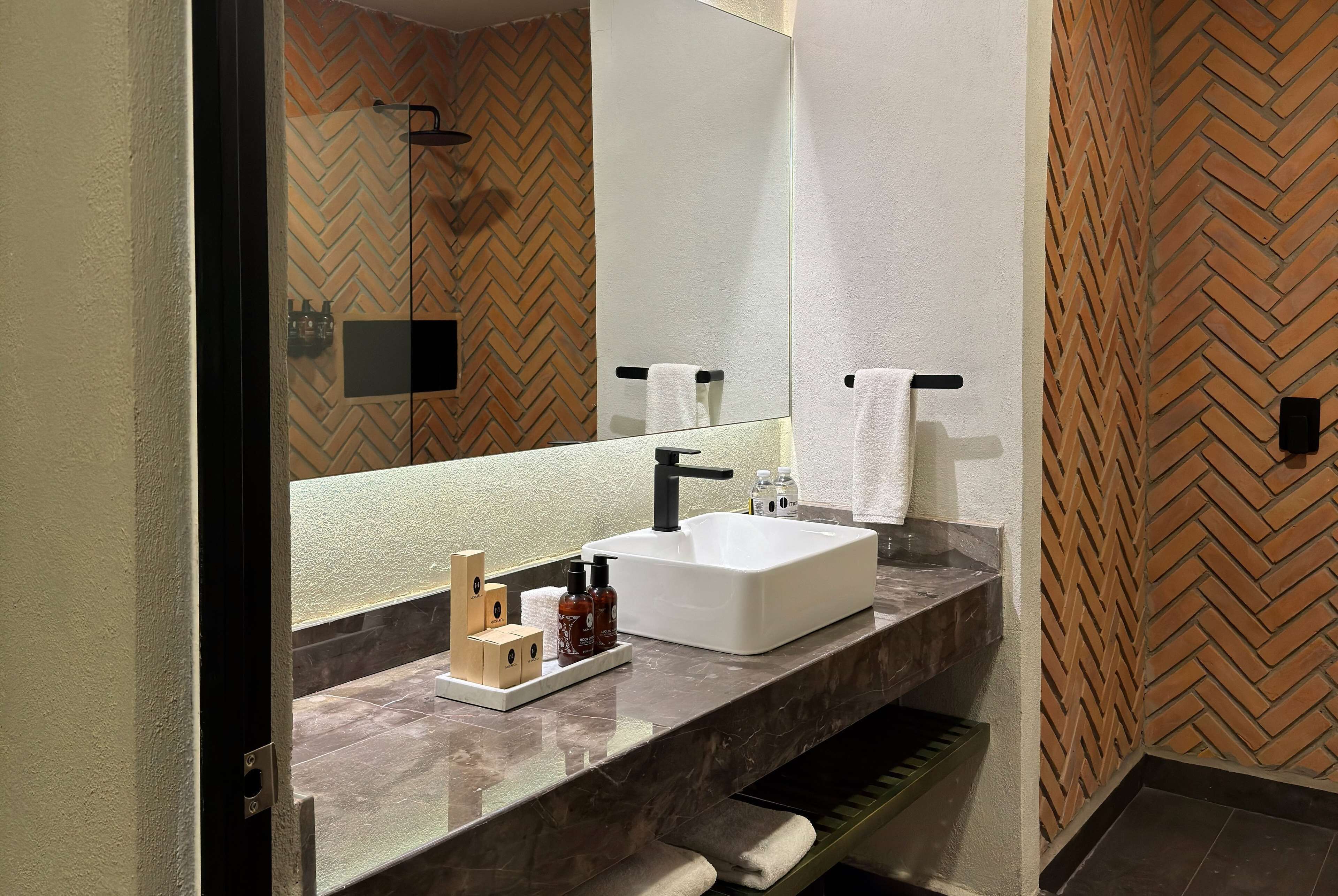 Un baño moderno con un espejo grande, un lavamanos blanco y un revestimiento de pared con motivo de espinilla.