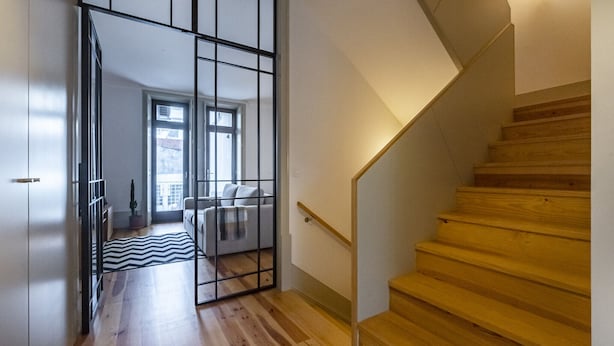 Un intérieur moderne avec un escalier en bois, une cloison en verre et une vue sur un balcon.