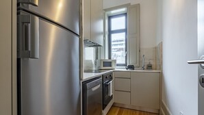 Une cuisine compacte dotée d’appareils électroménagers en acier inoxydable, d’un four à micro-ondes et d’une fenêtre située au-dessus de l’évier.