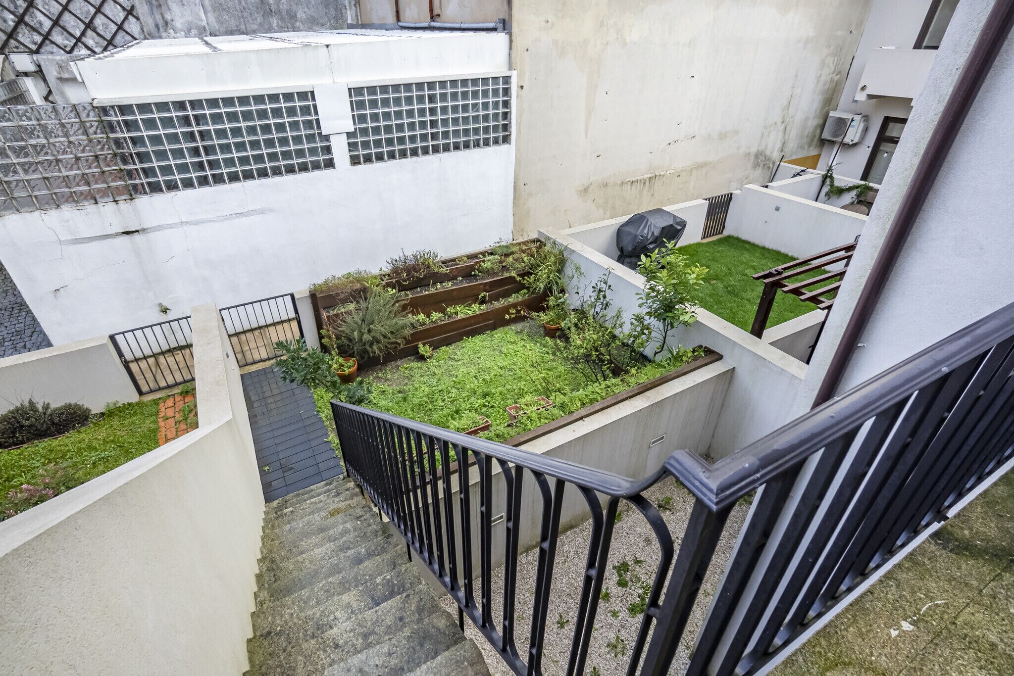 A residential building with a small garden area, a staircase, and a metal railing.