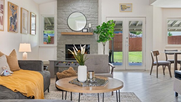 A living room with a fireplace, a sofa, a coffee table, and a dining area with chairs. - Your home away from home! (Round Rock)