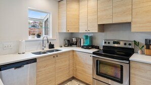A modern kitchen with wooden cabinets, a stainless steel dishwasher, a coffee maker, and an oven. - Your home away from home! (Round Rock)