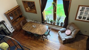 Ein geräumiger Wohnbereich mit einem Holzesstisch, einer gemütlichen Couch und einer Treppe mit bunten Wollknäueln.