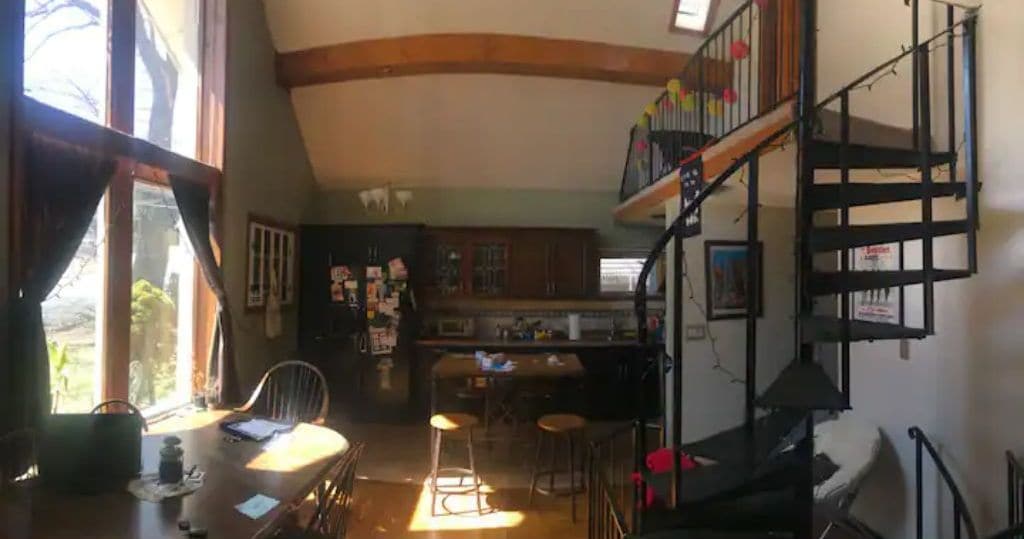A kitchen with a bar area, wooden beams on the ceiling, and a staircase leading to an upper level.