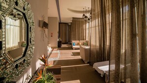 Ein Hotelzimmer mit einem großen, verzierten Spiegel, einer Couch, einem Bett und einer Treppe, die in einen anderen Raum führt.