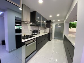 Una cocina moderna con estufa a gas, horno, microondas y refrigerador.