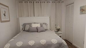 A neatly arranged bedroom with a bed, a bedside table, a nightstand, a lamp, and a wardrobe. - Global Bed & Breakfast (Pottsville)