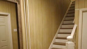 A staircase with wooden steps and white handrails, leading to a door with a mirror on the wall. - Global Bed & Breakfast (Pottsville)