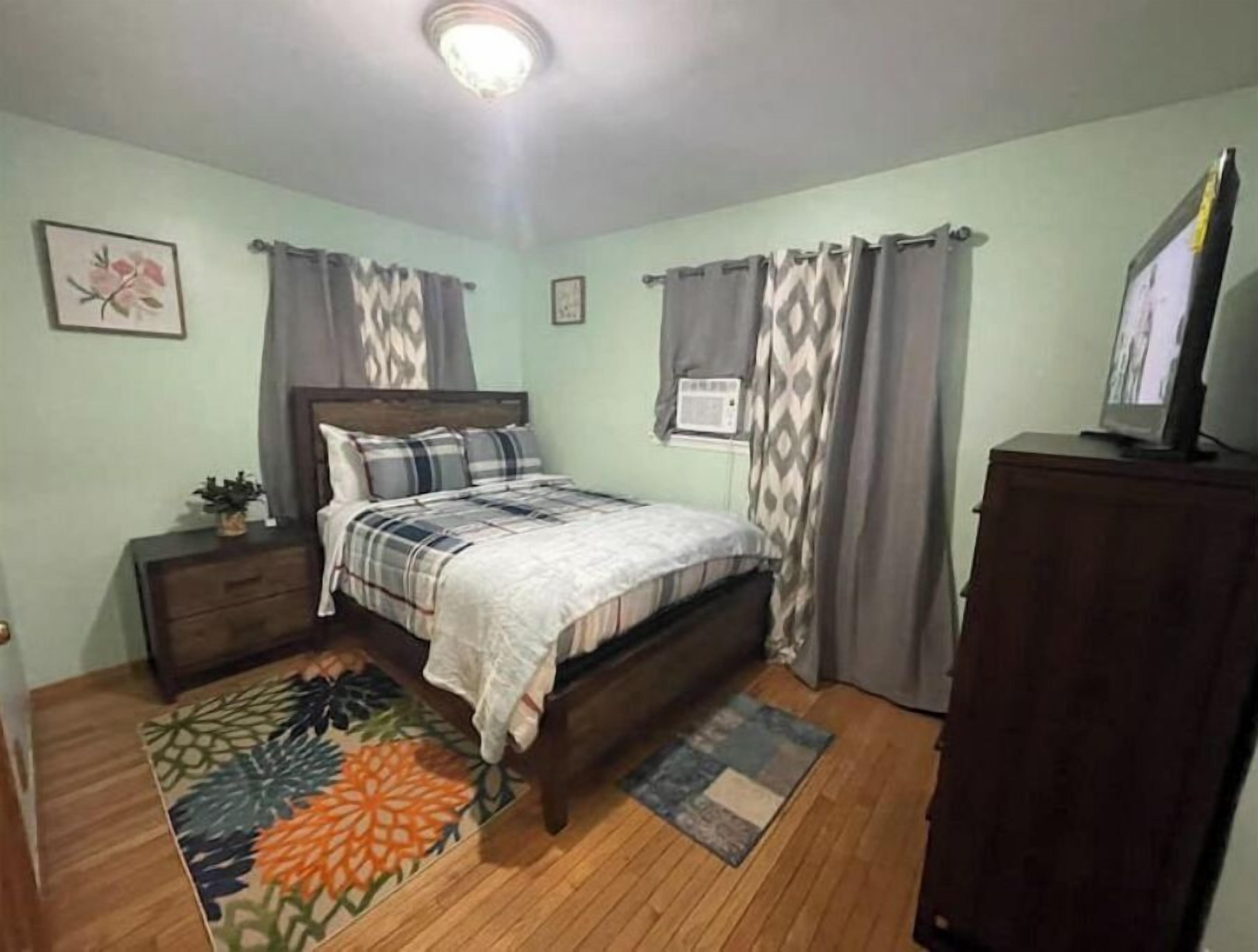 A bedroom with a bed, a nightstand, a dresser, and a ceiling light.