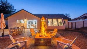 Eine gemütliche Außenpatio mit Feuerschale, Holzstühlen und Esstisch.