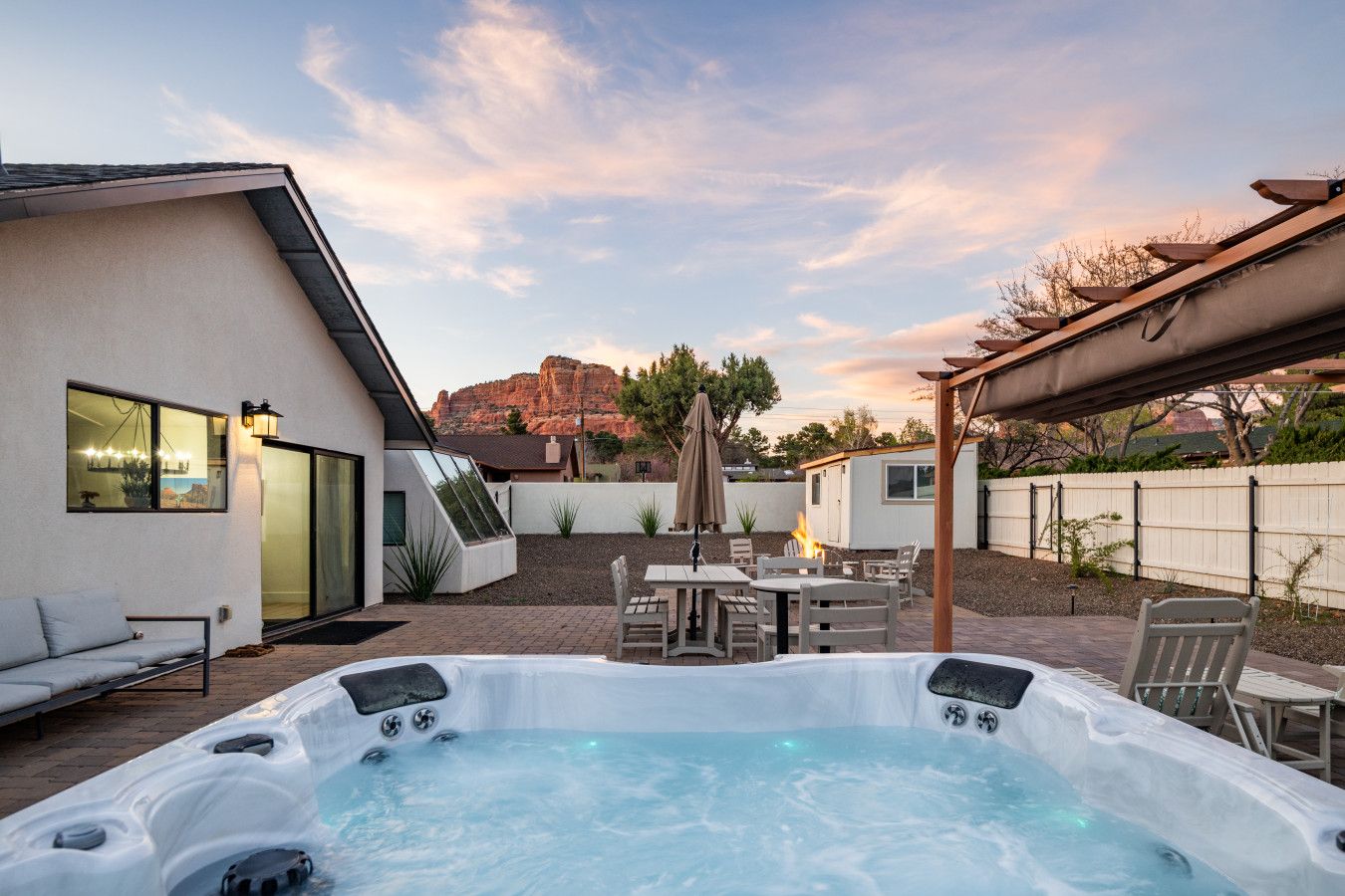 A backyard with a hot tub, outdoor seating, and a view of a mountain.