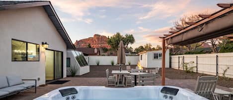 A backyard with a hot tub, outdoor seating, and a view of a mountain.