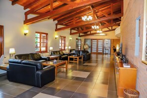 A spacious lobby with leather sofas, wooden tables, and a reception desk. - Nobile Hotel Papillon (Bella Vista)