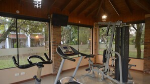 Un gimnasio con equipo de ejercicio, ventanas amplias y vistas al exterior.