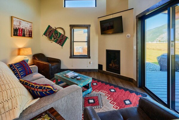 Una sala de estar acogedora con chimenea, un ventanal y vistas al exterior.