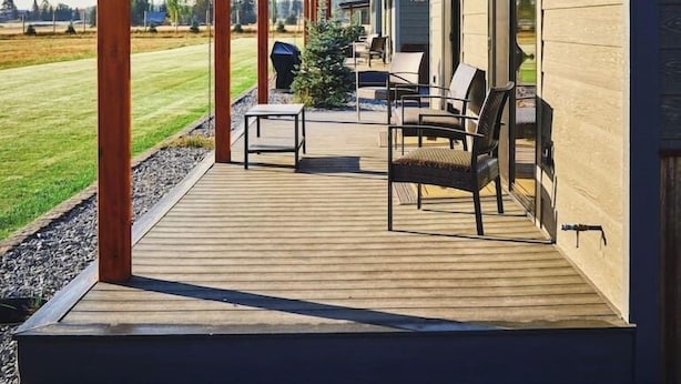 A covered outdoor deck with wooden flooring and metal chairs. - Blaine Cabin-Stunning Mountain Views,Close to GNP! (Columbia Falls)