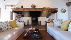 A cozy living room with a fireplace, two sofas, and a coffee table with a book and fruit basket. - Villa Montelisi, With The most Unique View On Siena (6km) (Siena)