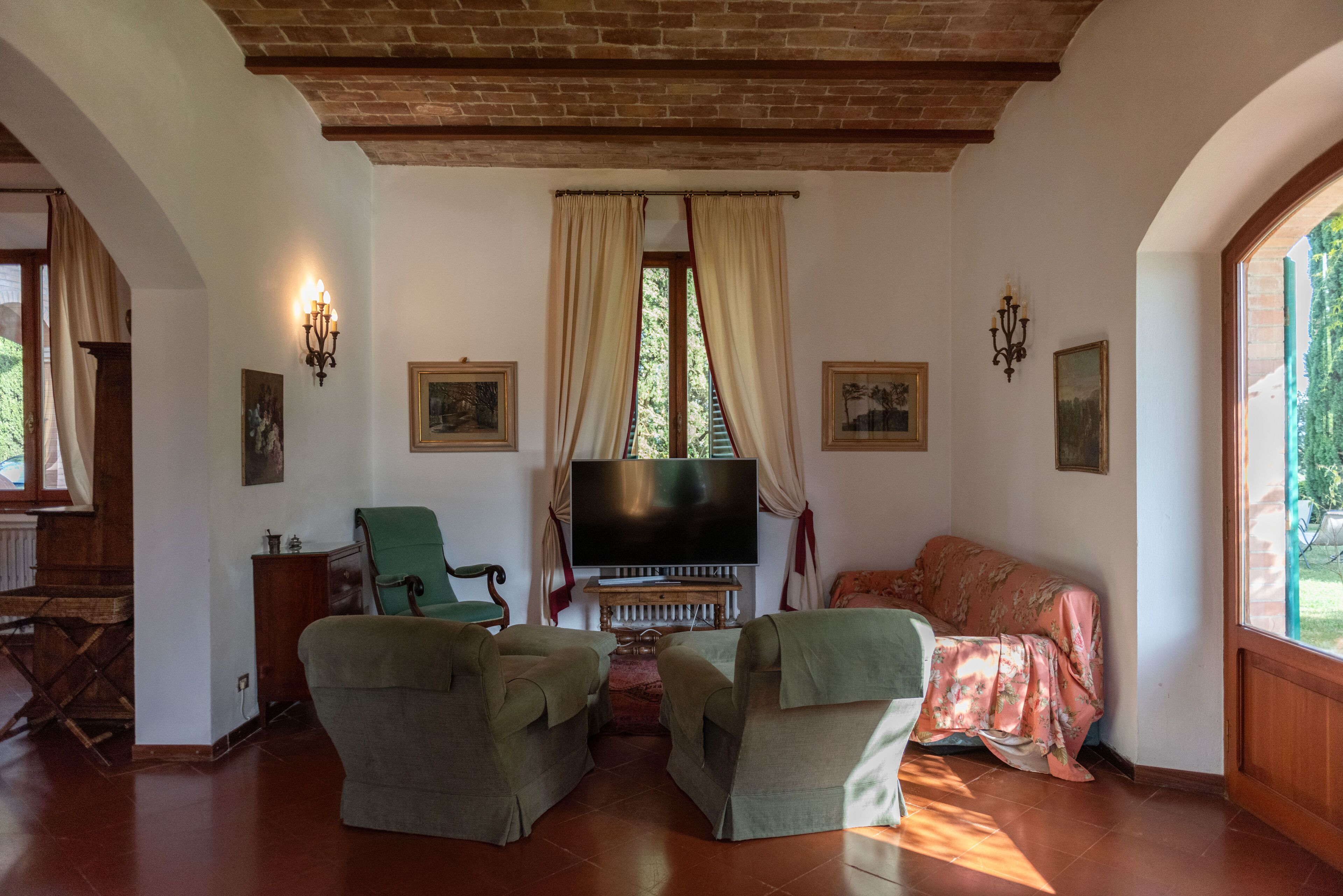 Una sala de estar acogedora con televisión, dos sillones, un sofá y una escalera de madera.